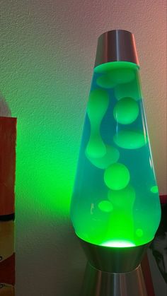 a green lamp sitting on top of a table next to a white and black wall