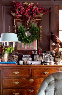 a christmas wreath is hanging on the wall above a dresser with candles and other holiday decorations