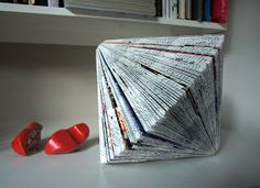 an origami folded book sitting on top of a table next to red shoes