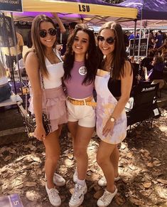 three young women standing next to each other under a tent