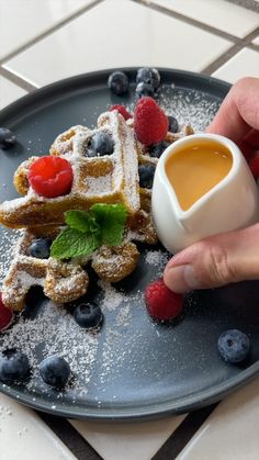 a plate with waffles covered in powdered sugar and berries