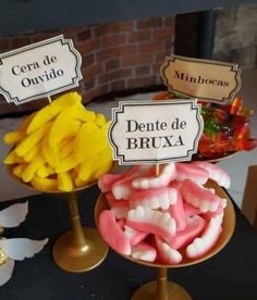 three different types of candies on top of gold pedestals with signs above them