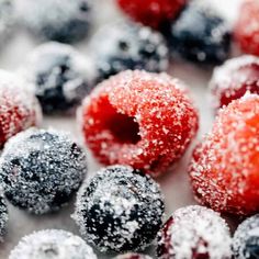 berries and powdered sugar covered donuts on a white surface