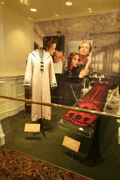 a display case with an old fashion dress and other items