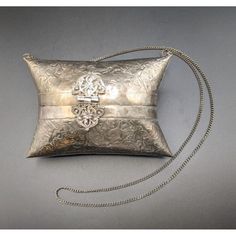 an old silver purse with a chain hanging from it's side on a gray surface