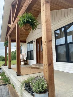 a porch covered in plants and potted plants next to a building with large windows