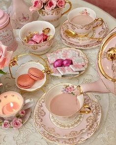 pink and gold tea set on a table with flowers in vases, plates, cups and saucers