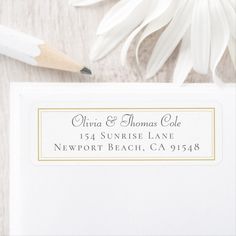 a close up of a white envelope with a pencil on it next to some flowers