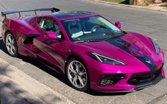 a pink sports car is parked on the street