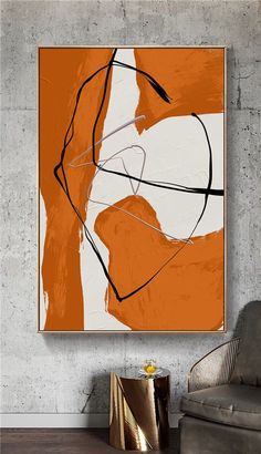 an orange and white abstract painting hangs on the wall next to a chair in a living room