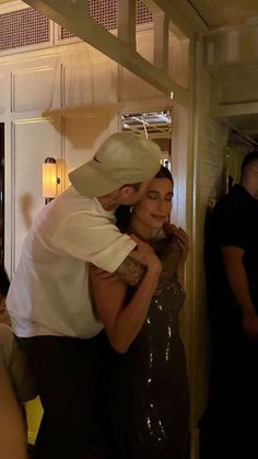 a man in a cowboy hat hugging a woman at a party with other people standing around