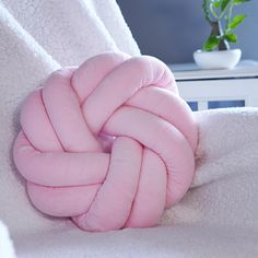 a pink knot on top of a white blanket next to a green potted plant