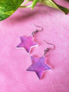 iridescent acrylic choice of sterling silver .925 or surgical stainless steel approximately 2" long in full length (from top of metal to bottom of acrylic), 1 1/8" wide made from an iridescent acrylic, these star earrings bring a groovy retro 1970s or 1980s vibe and lovely pastel rainbows this product is made to order, colors may appear slightly different care: the acrylic and metal can be cleaned with a light cleaner Rainbow Star-shaped Jewelry With Star Charm, Handmade Rainbow Star Jewelry, Trendy Purple Star-shaped Jewelry, Trendy Purple Star Shaped Jewelry, Trendy Purple Star Jewelry, 2000s Earrings, Star Dangle Earrings, Iridescent Acrylic, Goth Earrings