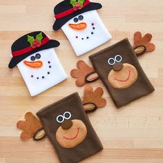 three christmas themed appliques are sitting on a wooden surface, one is wearing a hat and the other has reindeer antlers