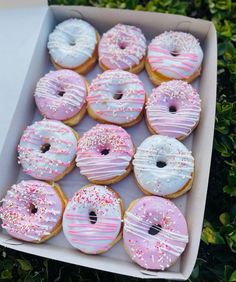 a box filled with pink and white donuts covered in sprinkled frosting