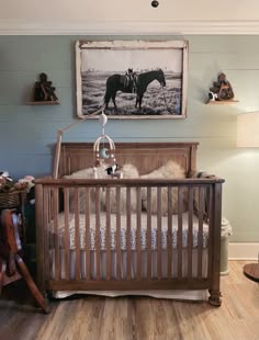 a baby's room with a wooden crib and horse pictures on the wall