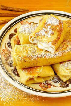 some crepes are on a plate with powdered sugar and cinnamon sprinkles