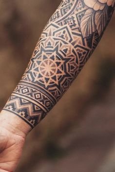 a man's arm with an intricate tattoo design on his left forearm and wrist