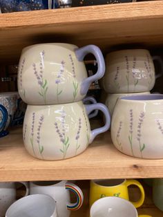 a shelf filled with lots of different colored coffee mugs