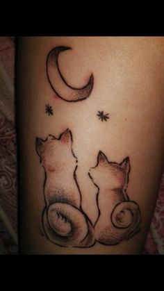 a couple of cats sitting next to each other under the moon and stars tattoo on someone's leg