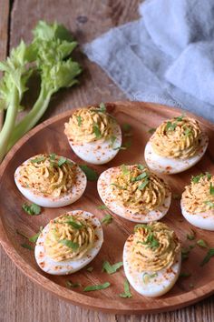 deviled eggs with mustard and parsley on a wooden plate