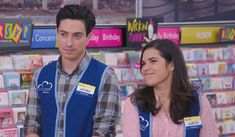 a man and woman standing next to each other in front of a store display filled with books