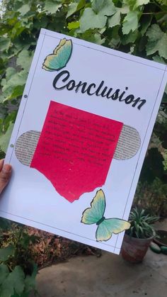 a person holding up a sign with the words conclusion written on it in front of some plants