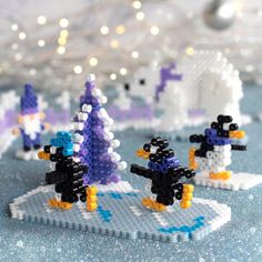 some lego penguins are standing in front of christmas trees and snowflakes on a table