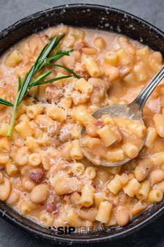 a bowl filled with macaroni and cheese on top of a black table next to a spoon