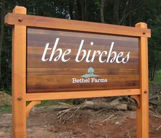 a wooden sign that says the burches in front of some trees and dirt