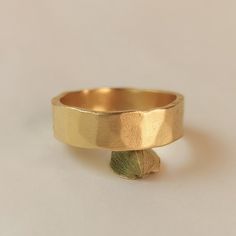 a close up of a gold ring on a white surface with a flower in the middle