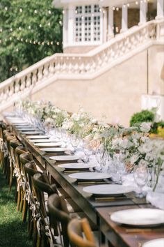 the long table is set with flowers and place settings for dinner guests to sit at