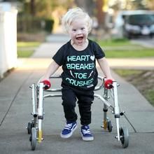 a little boy that is sitting on a small walker with his mouth open and tongue out