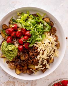 a white bowl filled with lettuce, tomatoes and other vegetables next to a container of dressing