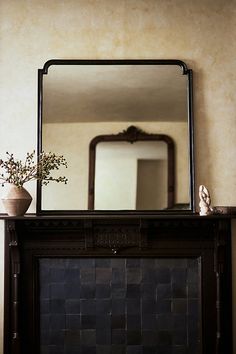 there is a mirror and vase on the mantle