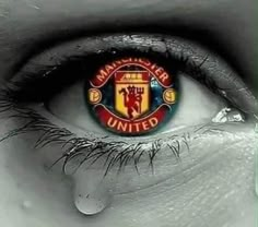 the manchester united logo is reflected in an eye with water droplets on it's iris