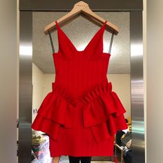 a red dress is hanging on a hanger in front of a mirror and it's reflection