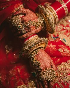 the bride's hands are covered in gold and red bridals, while she wears