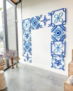 a blue and white wall hanging on the side of a building next to potted plants