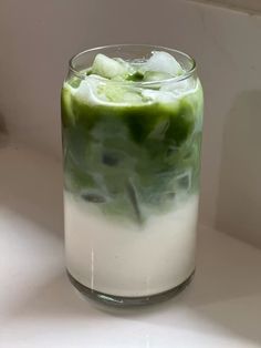 a glass filled with green and white liquid