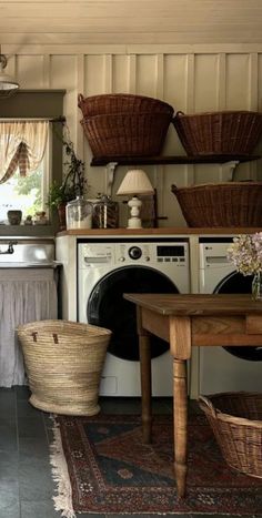 an old fashioned washer and dryer in a room with baskets on the wall