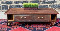 an old coffee table with two drawers and grass growing out of it