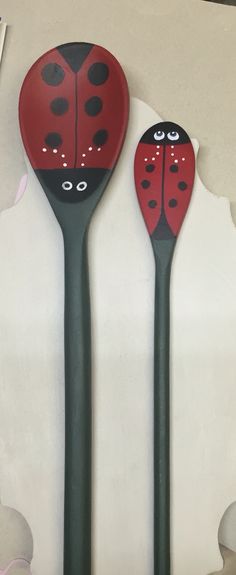 three black and red spoons with ladybugs painted on them, sitting next to each other