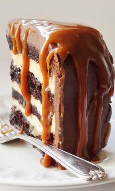 a piece of chocolate cake with caramel drizzled on top, sitting on a white plate