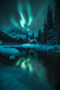 the aurora lights shine brightly over a snowy mountain lake and cabin in the foreground