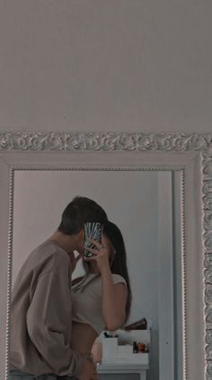 a man and woman standing in front of a mirror