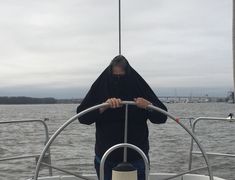 a person wearing a black hoodie standing on a boat