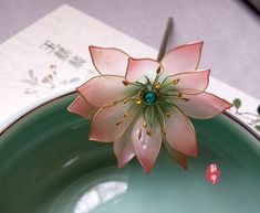 a pink flower sitting on top of a green bowl