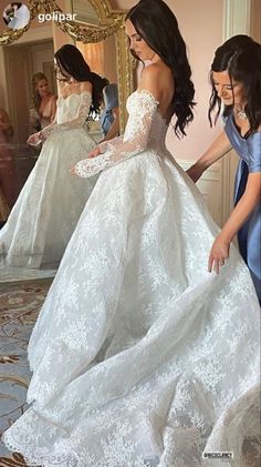 a woman in a white wedding dress looking at her reflection in the mirror while another woman is wearing a blue gown