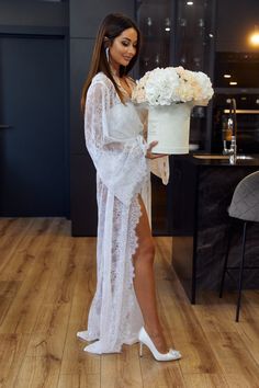 a woman in white dress holding a cake with flowers on it and posing for the camera